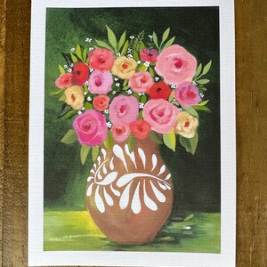May include: A floral painting featuring a brown vase with white decorative accents, filled with a bouquet of pink, red, and yellow roses and green leaves. The background is a dark green with a lighter green base.