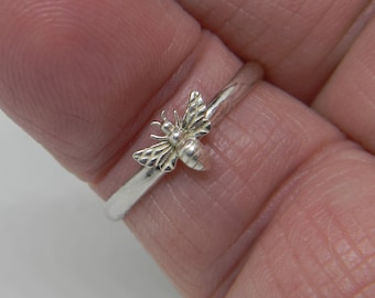 May include: A silver ring with a small bee design. The bee is detailed with wings and a body.