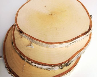 May include: Three round wooden slices, stacked on top of each other. The slices are made of birch wood and have a natural, light brown colour. The edges of the slices are slightly rough and have a natural bark texture.