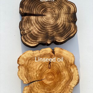 Puede incluir: Dos rodajas de madera, una con un acabado quemado y la otra acabada con aceite de linaza. La veta de la madera es visible en ambas rodajas.