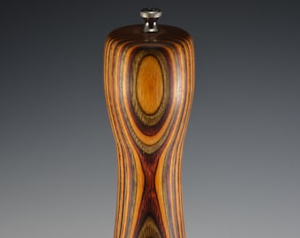 May include: A wooden pepper mill with a dark brown, orange, and red striped pattern. The mill has a silver top.