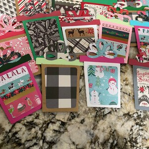 May include: A collection of handmade Christmas gift tags featuring various holiday designs, including snowmen, plaid patterns, and the words "Falala" and "Compliments of the Season".