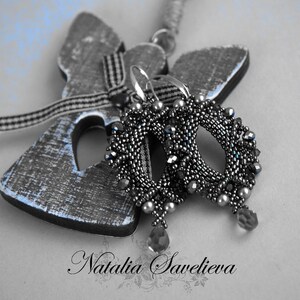 Puede incluir: Un par de pendientes de cuentas plateadas con un colgante de cristal en forma de l&aacute;grima. Los pendientes cuelgan de una figurita de &aacute;ngel de madera.