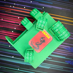 May include: Green game box with a red card that says "Snake" on it. The box has four green number dials with white numbers. The dials are labeled with numbers 0-9.