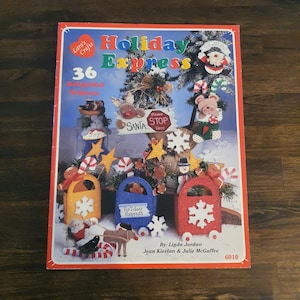 May include: A book cover titled "Holiday Express" by Lara's Crafts, featuring 36 delightful projects. The cover displays colorful Christmas-themed crafts, including Santa, reindeer, and snowflake designs. The book is by Linda Jordan, Jean Kievlan & Julie McGuffee.