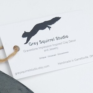 May include: A white rectangular tag with a black squirrel silhouette and the text Grey Squirrel Studio, Gravestone Impression Inspired Clay D&eacute;cor and Jewelry, Unique - Unusual - Uncommon, Handmade in Garrettsville, OH, greysquirrelstudio.etsy.com.