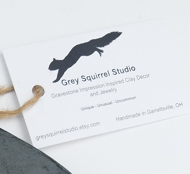 May include: A white rectangular tag with a black squirrel silhouette and the text Grey Squirrel Studio, Gravestone Impression Inspired Clay D&eacute;cor and Jewelry, Unique - Unusual - Uncommon, Handmade in Garrettsville, OH, greysquirrelstudio.etsy.com.