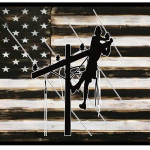 May include: A black and white silhouette of a worker on a power line pole against a distressed wood American flag background.