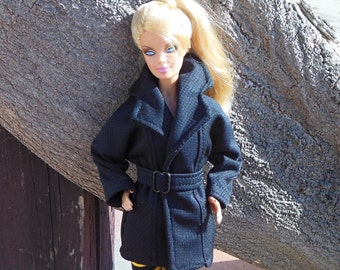 May include: A blonde doll wearing a black coat with a belt and black and yellow striped leggings.