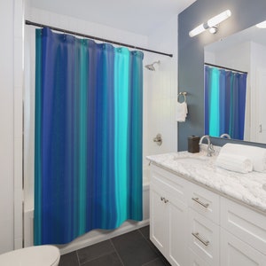 May include: A blue and turquoise striped shower curtain with a white bathroom vanity and a white sink.