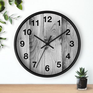 May include: Black and white clock with a wood grain design. The clock face has black numbers and hands.