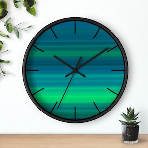 May include: A black framed wall clock with a green and blue abstract design. The clock face has black hour and minute hands.