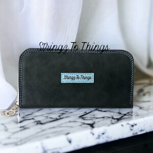 May include: A black leather zippered wallet with a blue and white label that reads "Stringz To Things".
