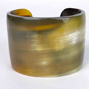 May include: A wide, brown and yellow horn cuff bracelet. The bracelet is made of polished horn and has a natural, organic look.