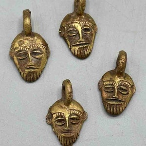 May include: Four gold-colored pendants with a face design. Each pendant has a loop at the top for hanging.