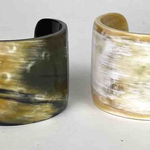 May include: Two horn bracelets, one with a black and brown pattern and the other with a white and brown pattern.