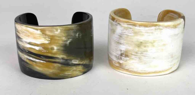 May include: Two horn bracelets, one with a black and brown pattern and the other with a white and brown pattern.