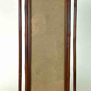 Puede incluir: Un marco de fotos rectangular de madera con un acabado marrón natural. El marco tiene un diseño vertical con detalles de estilo bambú en los laterales. El centro tiene un respaldo marrón claro.