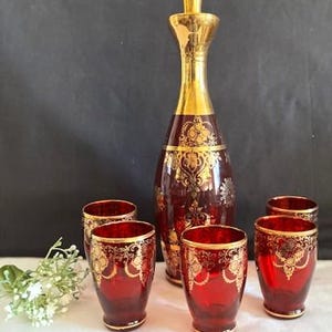 Pode incluir: Uma caneca de cerâmica branca com uma alça preta e o texto "But First, Coffee" em negrito preto. A caneca está sobre um fundo neutro, destacando seu design simples.