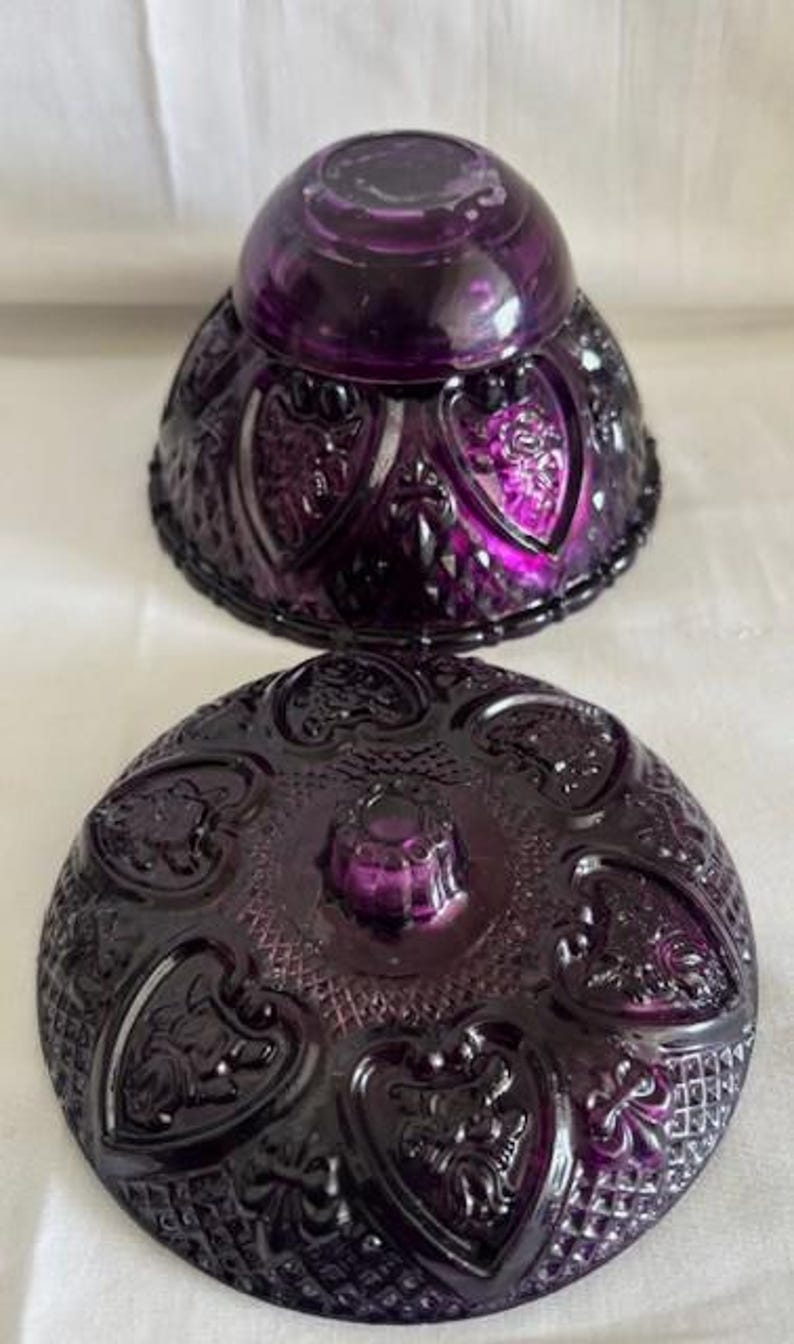 Puede incluir: Un platito de caramelo de vidrio morado vintage con una tapa abovedada. El plato y la tapa est&aacute;n decorados con un patr&oacute;n de coraz&oacute;n.