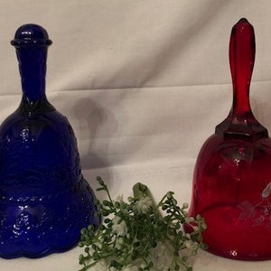 Puede incluir: Dos campanas de vidrio, una azul y otra roja, con diseños florales grabados. Las campanas son decorativas y tienen un aspecto vintage.