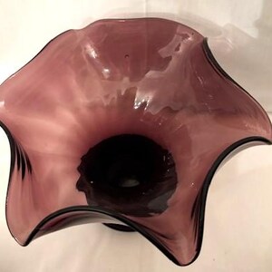 Puede incluir: Un jarr&oacute;n de vidrio morado grande con una abertura ancha y acampanada y un borde rizado. El jarr&oacute;n est&aacute; hecho de vidrio transparente con un tinte morado oscuro.