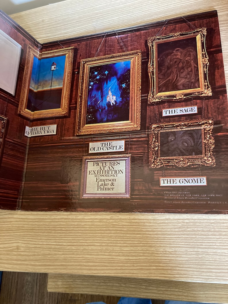 May include: A vintage record album cover featuring a series of framed paintings with titles like "The Hut of Baba Yaga", "The Old Castle", "The Sage", and "The Gnome". The album is for the musical composition "Pictures at an Exhibition" by Modest Mussorgsky, performed by Emerson, Lake & Palmer.