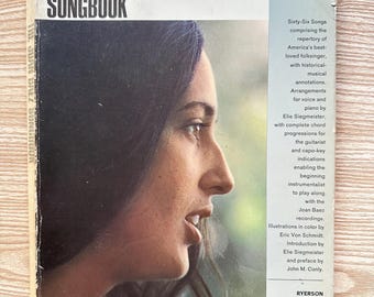 May include: The Joan Baez Songbook, a vintage book with a portrait of Joan Baez on the cover. The cover features the title in large, bold letters and details about the songs and arrangements. The book is in good condition.