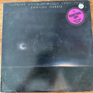 Può includere: Copertina dell'album "Quarter Moon in a Ten Cent Town" di Emmylou Harris. La copertina presenta un paesaggio scuro con una luna crescente e il titolo dell'album e il nome dell'artista. È presente un adesivo rosa "Promotional Copy".