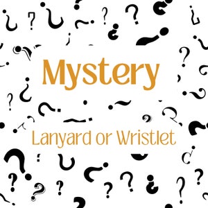 May include: A white background with black question marks scattered around the word "Mystery" in orange text. Below the word "Mystery" is the text "Lanyard or Wristlet" in black text.