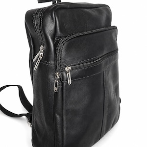 Puede incluir: Una mochila de cuero negro con forma rectangular vertical, que cuenta con múltiples compartimentos con cremallera, herrajes de metal plateado, un asa superior y correas ajustables para los hombros. La superficie exterior es lisa.