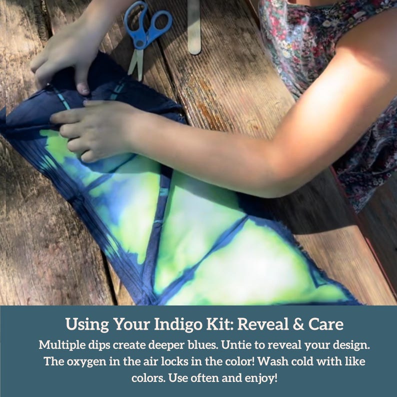 May include: A person is working on a tie-dye project. The fabric is folded and tied, revealing blue and green patterns. Scissors and a wooden stick are nearby. The text at the bottom says, "Using Your Indigo Kit: Reveal & Care."