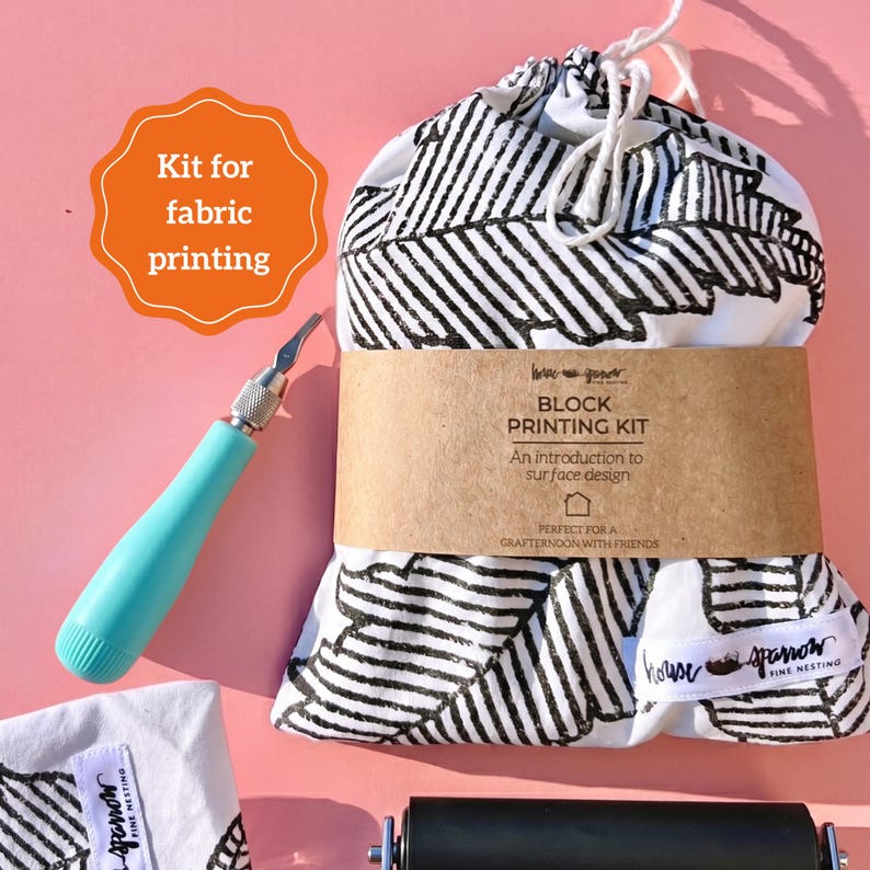 May include: A fabric printing kit with a teal handle carving tool, a black and white leaf-patterned drawstring bag, and a black roller. The kit includes a block printing kit with the text "An introduction to surface design."