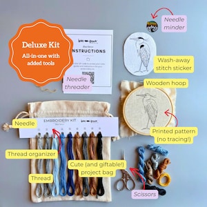 May include: An embroidery kit featuring a wooden hoop with a printed blue heron pattern, a project bag, thread organizer with nine colors of embroidery floss, a needle, scissors, a needle minder, a wash-away stitch sticker, and instruction card.