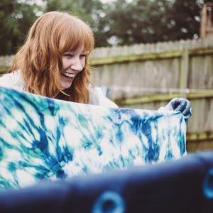 Group enjoying a bridal shower activity using a tie dye craft kit for adults. Hands dipping fabric into an indigo dye kit for beginner projects, creating custom bridal party tshirts and event decor.