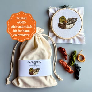 May include: An embroidery kit with a mallard duck design. The kit includes a printed fabric, embroidery hoop, threads, and a drawstring bag. The orange label reads "Printed -AND- stick-and-stitch kit for hand embroidery."