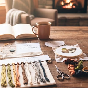Puede incluir: Un kit de punto de cruz con un dise&ntilde;o de pato en un bastidor de madera. El kit incluye hilo de bordar, tijeras e instrucciones. Una taza de caf&eacute; y un libro abierto est&aacute;n sobre una mesa de madera, creando un ambiente acogedor.