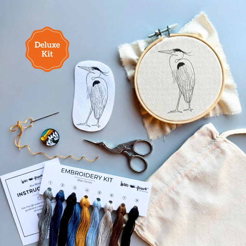 Pu&ograve; includere: Un kit da ricamo composto da un telaio in legno con un disegno di airone blu su tessuto, una toppa in tessuto con lo stesso airone, fili da ricamo in nove colori, un ago, forbici, un magnete per aghi e una scheda con scritto Deluxe Kit.