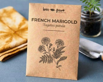 May include: A rectangular brown paper seed packet labeled House Sparrow Fine Nesting French Marigold Tagetes patula with a black ink botanical illustration of a marigold flower cluster and leaves centered on the front of the packaging.