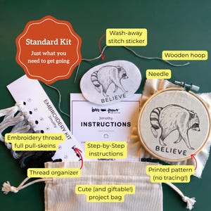 May include: An embroidery kit containing a wooden hoop with a raccoon pattern, a wash-away stitch sticker, embroidery thread on an organizer, a needle, step-by-step instructions, and a drawstring project bag. The kit is labeled Standard Kit.