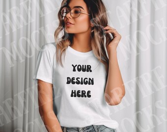 May include: White t-shirt with the text "YOUR DESIGN HERE" in a black, bold font. The shirt is a crew neck style and is being worn with blue jeans. The model is wearing glasses and has wavy hair.