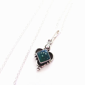 May include: A silver chain necklace with a pendant featuring a dark green gemstone set in a silver frame.