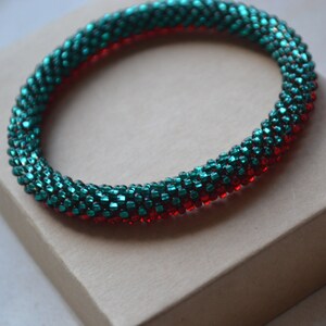 Puede incluir: Un brazalete de cuentas rojas y verde azulado con un diseño en espiral.