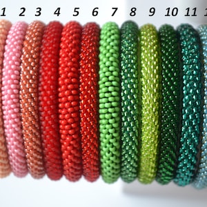 Peut inclure: Douze bracelets en perles de différentes nuances de rose, rouge, vert et bleu. Les bracelets sont numérotés de 1 à 12.