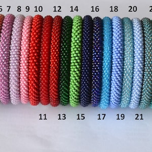 Può includere: Ventisette braccialetti di perline in vari colori, tra cui beige, giallo, marrone, lavanda, rosa, rosso, verde, blu, turchese, marrone, grigio e nero. I braccialetti sono numerati da 1 a 27.