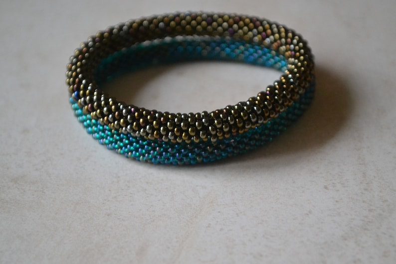May include: A beaded bracelet with a gradient of blue, green, and gold beads.