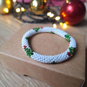 May include: White beaded bracelet with green and red Christmas tree designs.