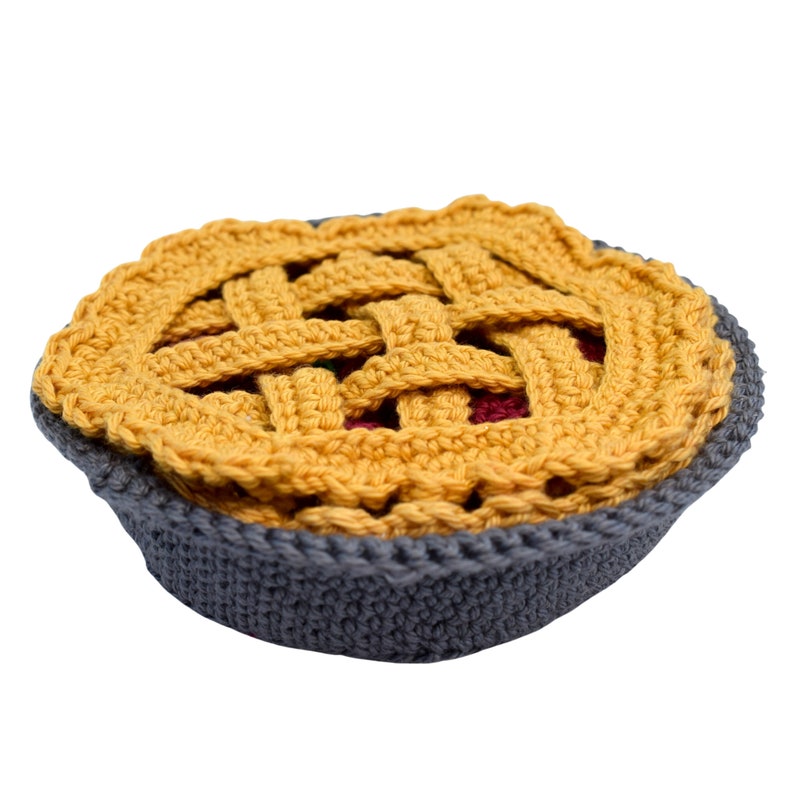 Puede incluir: Un pastel de crochet con una corteza amarilla y un molde para pastel gris. El pastel es un art&iacute;culo artesanal hecho a mano.