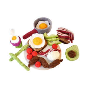 K&ouml;nnte beinhalten: Ein geh&auml;keltes Fr&uuml;hst&uuml;cksspiele-Set mit einer Bratpfanne, Eiern, Toast, Speck, Avocado und Tomaten. Das Set ist aus weichem Garn gefertigt und perfekt f&uuml;r Rollenspiele.