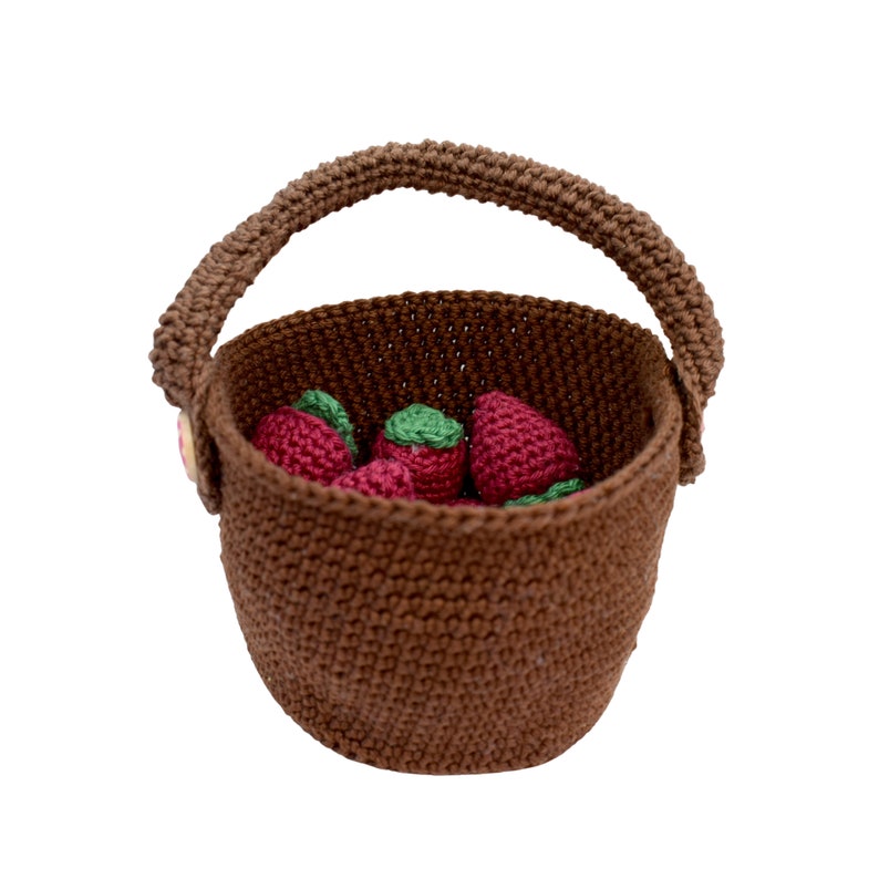 Puede incluir: Una cesta de crochet marr&oacute;n con asa llena de fresas de crochet rojas.